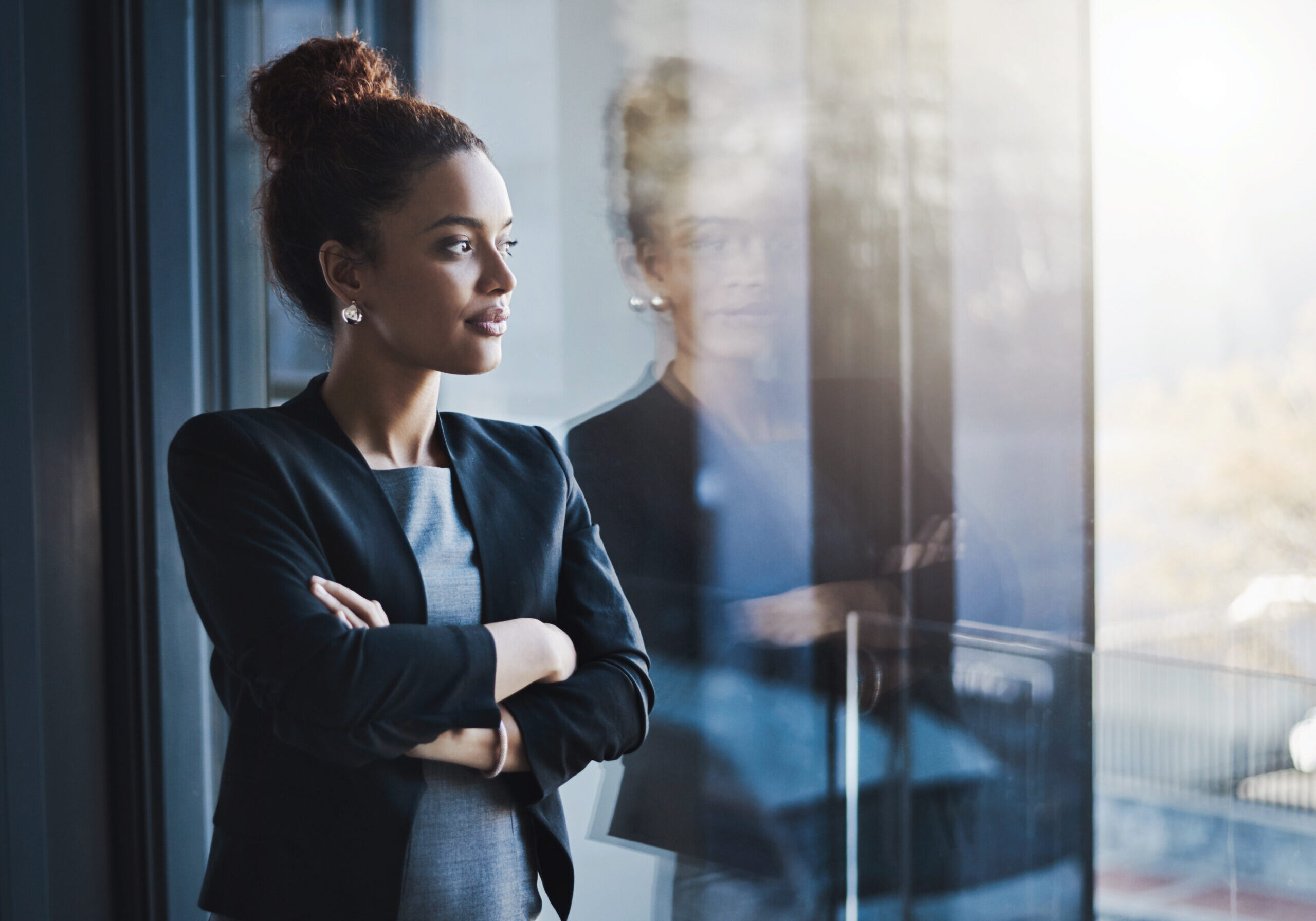 Shot of a young businesswoman looking out the window in an office